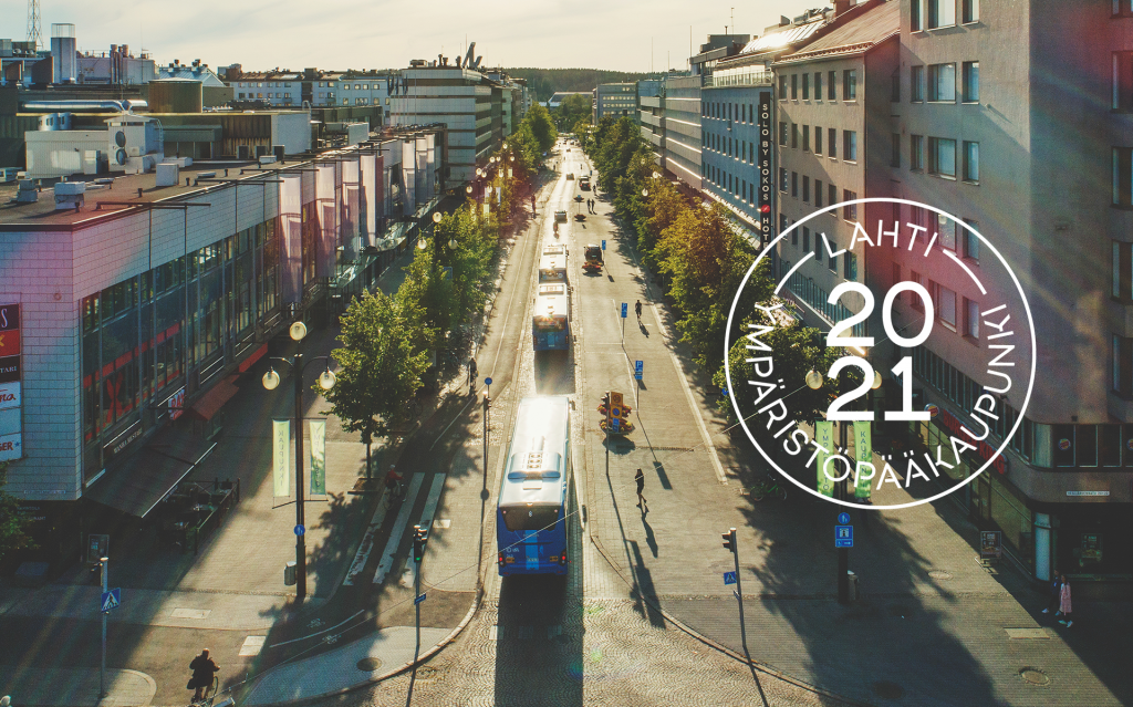 Kesäinen ilmakuva busseista Aleksanterinkadulla ja kuvan päällä Lahti ympäristöpääkaupunki 2021 leima.